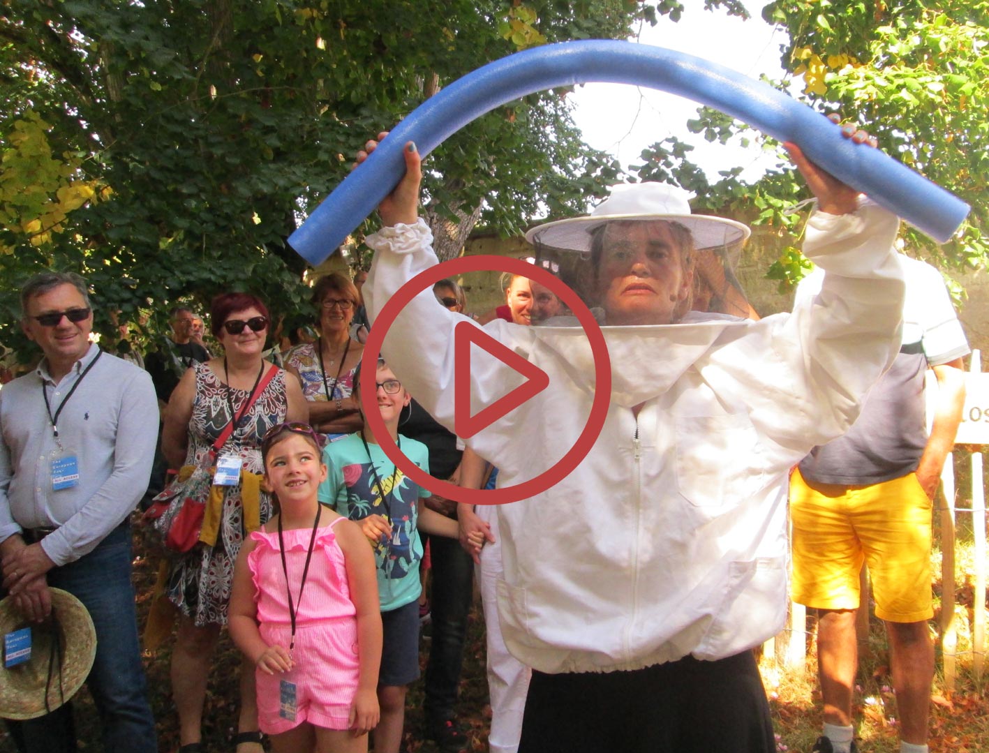 Le personnage Sylvie Lamour a revêtu une vareuse d'apiculteur et tient
            	entre ses mains une frite de piscine en mousse bleue. Son regard est sérieux.
            	Derrière elle on voit le public qui a le sourire aux lèvres. Photo prise à Sougé
            	Loir-et-Cher.